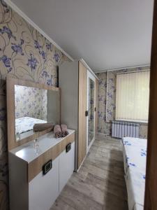 a bedroom with a bed and a mirror on the wall at Симпатичная квартирка рядом с парком! in Almaty