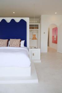 a bedroom with a white bed with a blue headboard at La Playa, Bali in Munggu