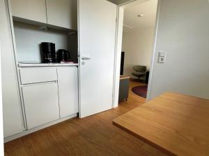 Habitación con cocina con nevera y mesa. en Discover Langeoog Comfortable apartment with SPA and pool en Langeoog