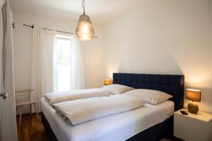 una camera da letto con due letti con lenzuola bianche e una finestra di Seeapartment Da Leopoldo II a Velden am Wörthersee