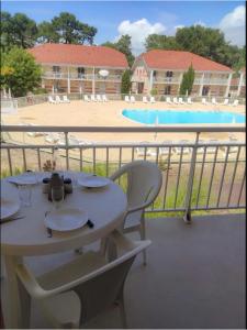 - une table sur un balcon avec vue sur la piscine dans l'établissement Résidence des A Indépendant, au Le Verdon-sur-Mer