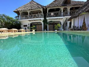 a swimming pool in front of a house at Olamanga Beach Villa in Jambiani