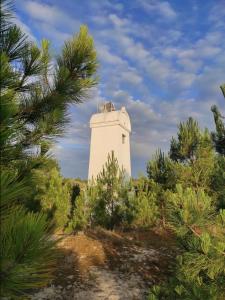 un phare blanc au milieu des arbres dans l'établissement Résidence des A Indépendant, au Le Verdon-sur-Mer