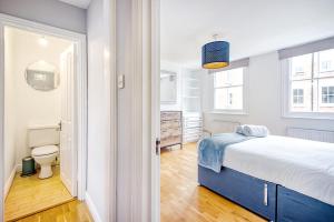 a white bedroom with a bed and a bathroom at Marylebone Duplex Apartment in London