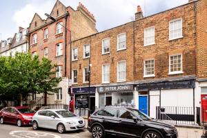two cars parked in front of a brick building at Marylebone Duplex Apartment in London