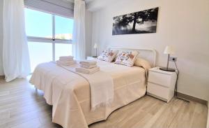 Un dormitorio blanco con una cama con toallas. en Amplio y cómodo apartamento., en Granadilla de Abona
