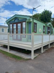 una pequeña casa verde con una valla blanca en Cosy comfort en Ingoldmells