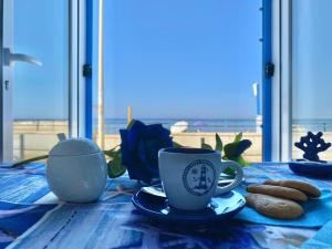 a table with two coffee cups and cookies on it at Blue Velvet in Punta Secca