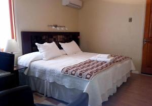 1 dormitorio con 1 cama grande con almohadas blancas en Atankalama, en Calama