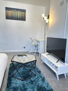 a living room with a flat screen tv and a coffee table at Courtyard Stay in Norwich