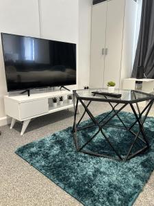 a living room with a tv and a glass table at Courtyard Stay in Norwich
