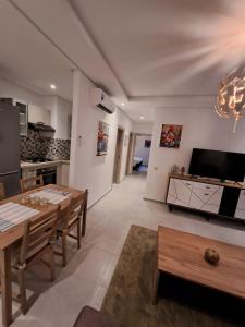 ein Wohnzimmer mit einem Tisch und einer Küche in der Unterkunft COSTA MAR MARTIL 2 TETOUAN in Martil