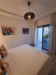 馬提的住宿－COSTA MAR MARTIL 2 TETOUAN，卧室配有一张白色大床和吊灯。