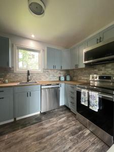uma cozinha com armários brancos e electrodomésticos pretos em Modern, Sunset Waterfront Cottage with EV Charger em Yarker