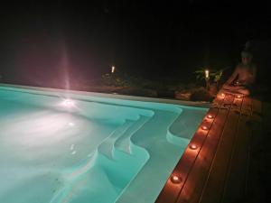 a woman sitting next to a swimming pool at night at La Grange de Cablanc in Monestier