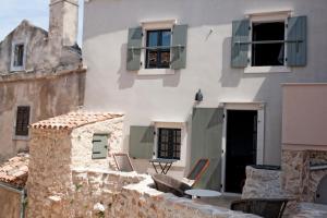 ein Gebäude mit Stühlen und einem Tisch auf dem Balkon in der Unterkunft Sisters-Homes Vidovići 9 in Martinšćica