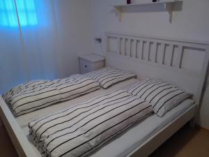 a white bed with striped sheets in a bedroom at Ferienwohnung Strandnest Sierksdorf in Sierksdorf