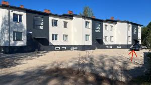 un grand bâtiment blanc et noir avec un parking dans l'établissement Rõuge Apartment, à Rõuge