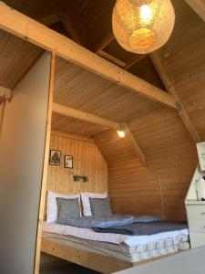 a bed in a wooden room with a ceiling at Nexø Camping & Cabins in Neksø