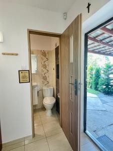 a bathroom with a toilet and a sliding door at Róża Wiatrów in Sztutowo