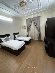 una habitación de hotel con 2 camas y un piano en شهد الثانية للشقق المخدومة, en Al ‘Abābīd