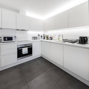a white kitchen with white cabinets and appliances at Stunning 2 Bed 2 Bath Apartment in Clerkenwell in London