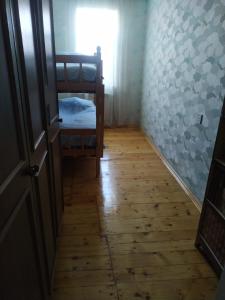 a hallway with a bedroom with a bed and a wooden floor at Friends Guest House in Ganja