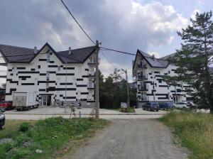 un grand bâtiment blanc avec des voitures garées dans un parking dans l'établissement Studio Triangle Divcibare, à Divčibare