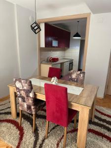 a wooden dining room table with two red chairs at Dada Lux in Kumanovo
