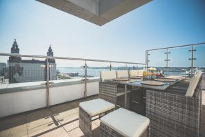 NOVU Apartments Liverpool Waterfront في ليفربول: شرفة على طاولة وكراسي في مبنى