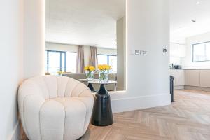 a white living room with a chair and a table at NOVU Apartments Liverpool Waterfront in Liverpool