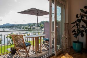 a balcony with a table and chairs and an umbrella at Seeapartment Da Leopoldo II in Velden am Wörthersee