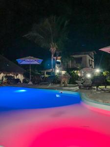 a pool at night with a blue and red pool at Pousada La Goduria in Canoa Quebrada