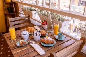 a wooden table with breakfast foods and orange juice at Trastevere Paper Suites in Rome