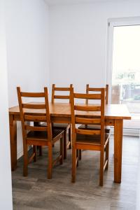 uma mesa de madeira com 4 cadeiras, uma mesa e uma janela em Dill Apartments Stederdorf em Peine