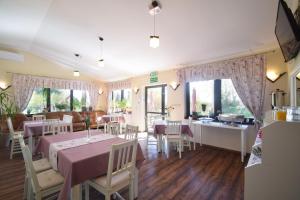 - une salle à manger avec des tables, des chaises et des fenêtres dans l'établissement Pensjonat Paskal, à Czerlejno