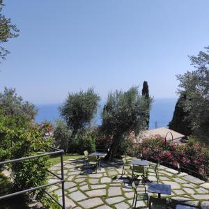 un patio in pietra con sedie, tavoli e l'oceano di Locanda Göghin a Pieve Ligure