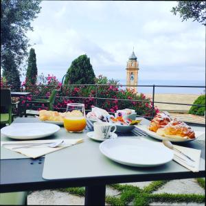 a table with plates of food and a clock tower in the background at Locanda Göghin in Pieve Ligure