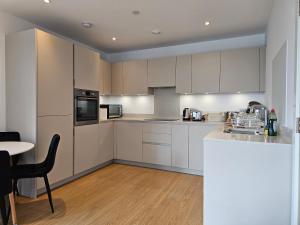 a kitchen with white cabinets and a table at Santina Apartments in Croydon