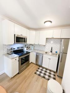 una cocina con armarios blancos y electrodomésticos de acero inoxidable en Retreat at Fenwick en Leonardtown