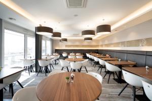ein Restaurant mit Holztischen und weißen Stühlen in der Unterkunft Fairotel in Filderstadt