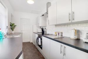 a white kitchen with white cabinets and a sink at Delightful Home in Seaham, Sleeps 4 in Seaham