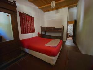 Un pequeño dormitorio con una cama roja en una habitación en Gran Casa Hostel&Camping en Tilcara