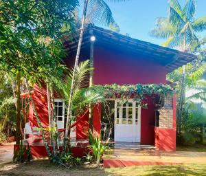 una casa roja con puertas blancas y palmeras en Casa Bromélia Red Itacaré, en Itacaré