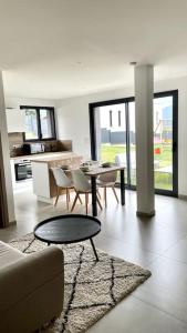 een woonkamer met een bank en een tafel en stoelen bij Logement neuf pour 4 personnes avec piscine in Chambéry