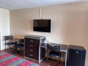 Habitación de hotel con escritorio y TV en la pared en Colonial Inn Hammond, en Hammond