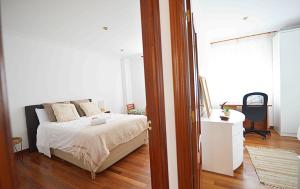 een slaapkamer met een bed met witte lakens en een raam bij Precioso apartamento en Santander in Santander