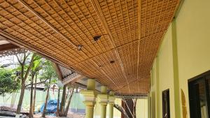a large wicker ceiling in a building with trees at A village home away from City in Ullāpāra