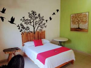 a bedroom with a bed with a tree and birds on the wall at Tribe Beachville in El Cuyo