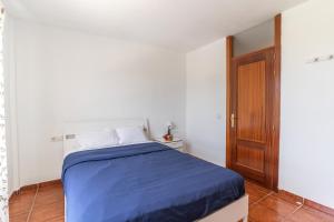 um quarto com uma cama com lençóis azuis e uma porta de madeira em Oceanfront Rainbow Costa Adeje 14V35 em Callao Salvaje